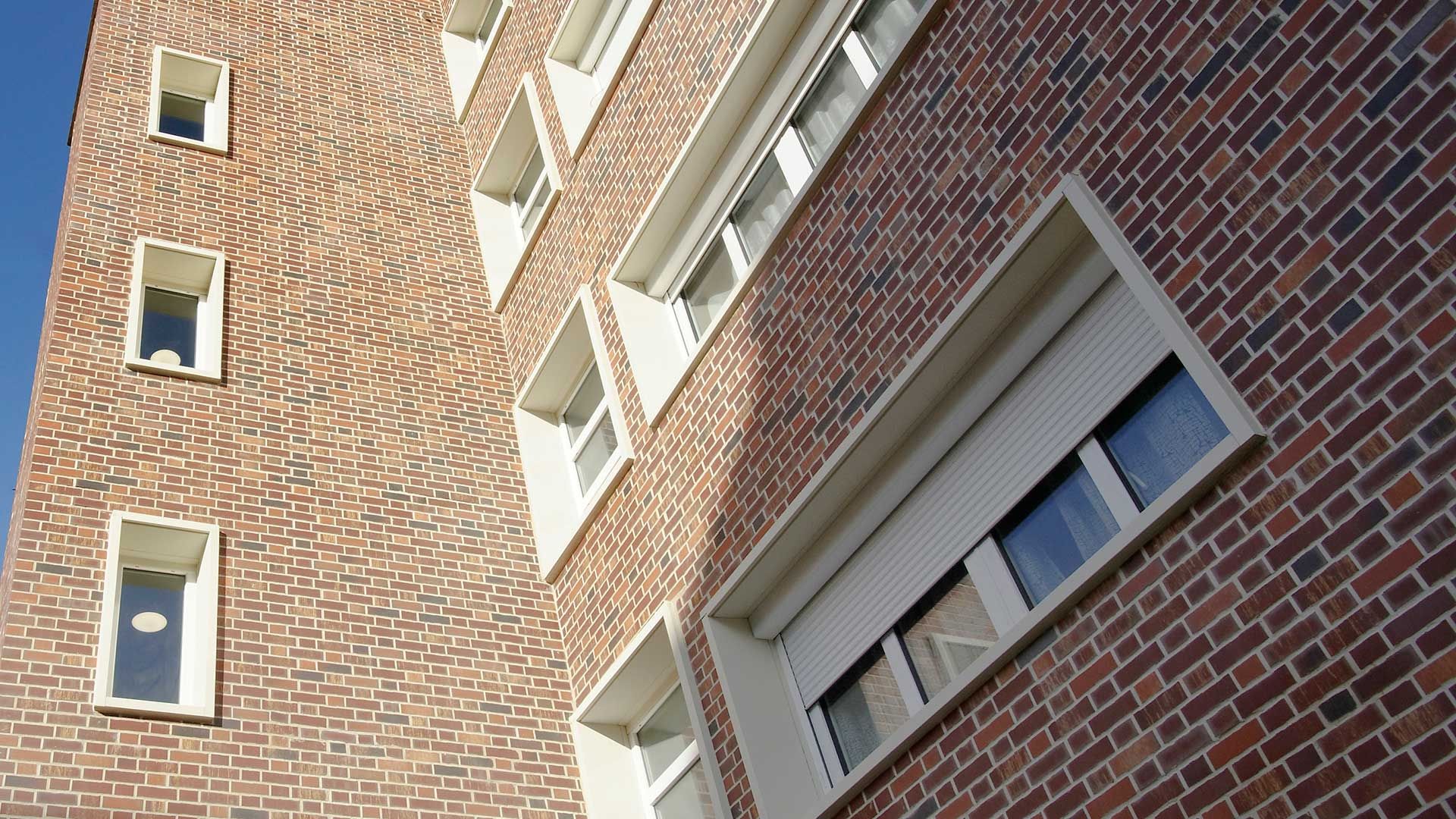 Ein Hochhaus mit einer Klinker Fassade und weißen Fensterrahmen.