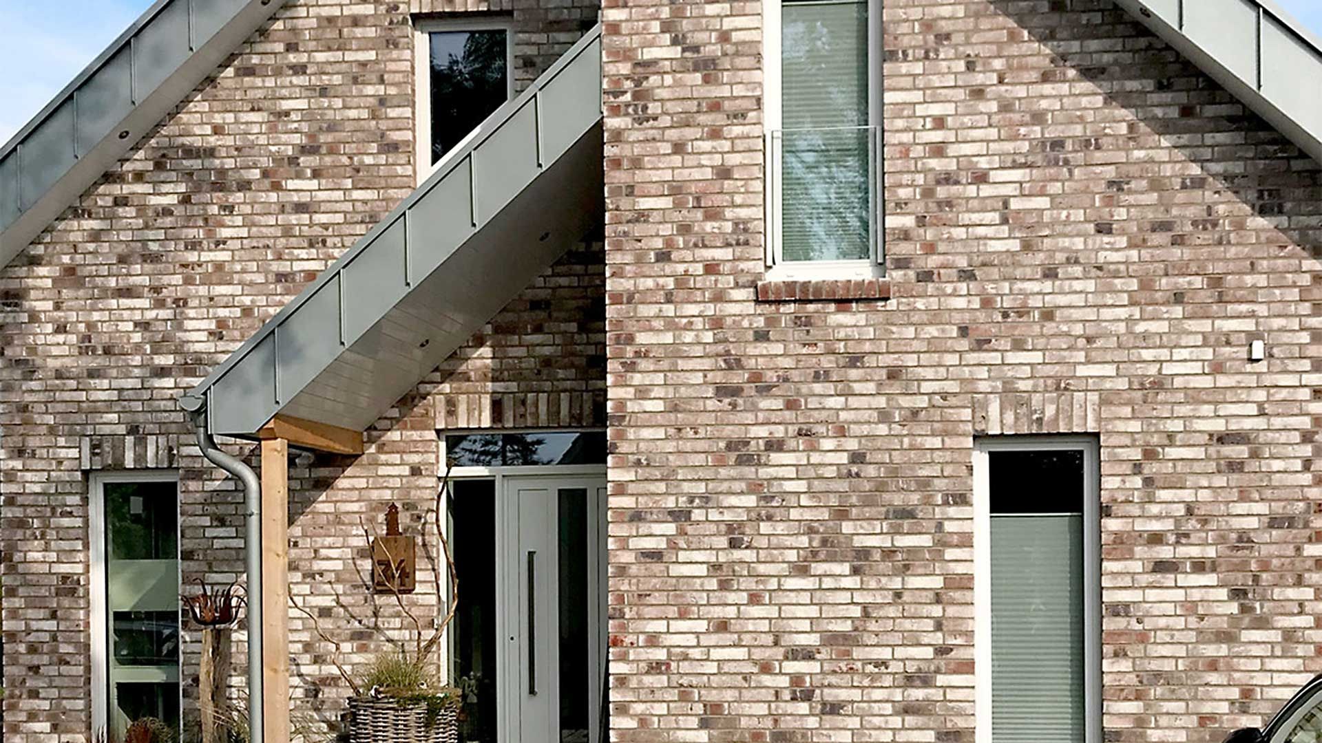 Ein Backsteinhaus mit einem Metalldach und einer Metaltür, das eine moderne und robuste Architektur verkörpert.